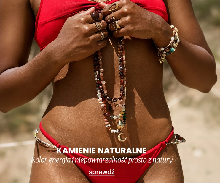 Letnia biżuteria VEZZI z kamieniami naturalnymi, trzymana w ręku przez modelkę o ciemnej karnacji, ubraną w czerwone bikini